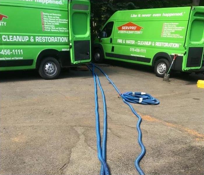 Two of our SERVPRO trucks with hoses coming out on a water loss job.