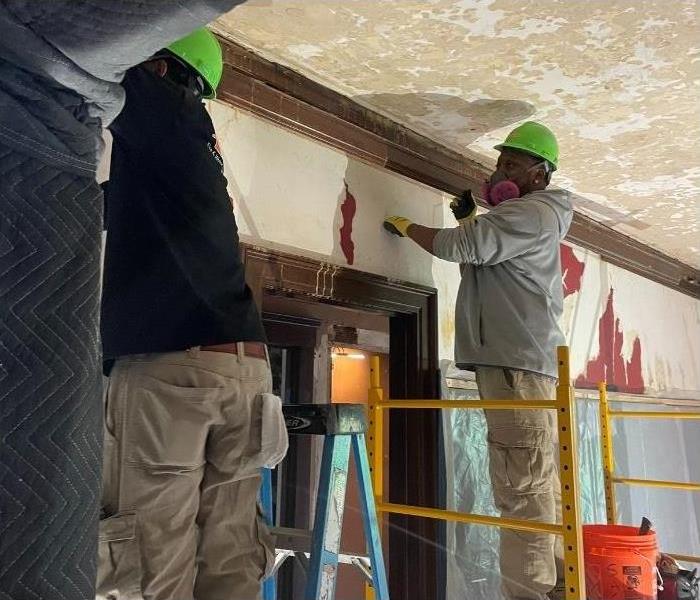 Two of our SERVPRO technicians working on water damage in the walls and ceiling.